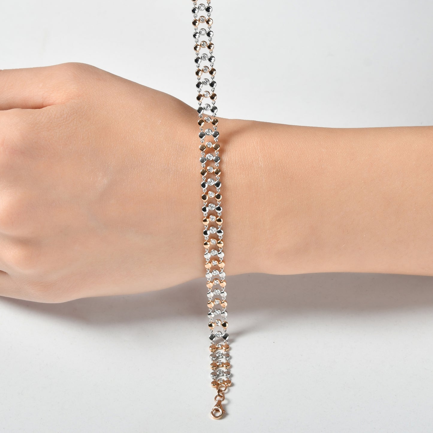 18 ayar beyaz ve rose altından üretilmiş örgü pırlanta bilezik, yuvarlak kesim taşların ışığı yansıtmasıyla göz alıcı bir görünüm kazandırıyor.