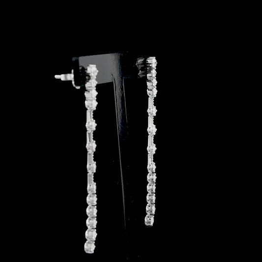 Sertifikalı pırlanta küpe, titizlikle seçilmiş yuvarlak kesim pırlantalarla ışığı kusursuz yansıtır çünkü 18 ayar beyaz altın gövde modern tasarımı tamamlar, ayrıca uzun sallantılı formu şık bir hediye alternatifi oluşturur.